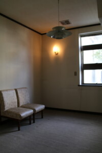 昭和の趣を残す2階洋室。応接間として使われた空間には、当時の照明や椅子が今も残ります。 旧高野寫眞舘2階にあるレトロな洋室と照明・応接用の椅子の様子