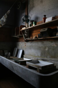 現像用トレイや吊るされた写真が残る暗室。昭和の写真づくりの現場がそのまま保存されています。 旧高野寫眞舘の暗室に残る写真現像用トレイと吊るされた印画紙の風景