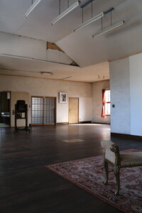 蛇腹式カメラや障子戸が残る、2階スタジオの全体風景。和と洋が混ざり合う写真館の中心です。 旧高野寫眞舘2階のメインスタジオ全景と蛇腹式カメラ、ラグ、障子のある空間